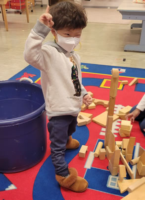 3-year-old celebrates his wooden block tower.